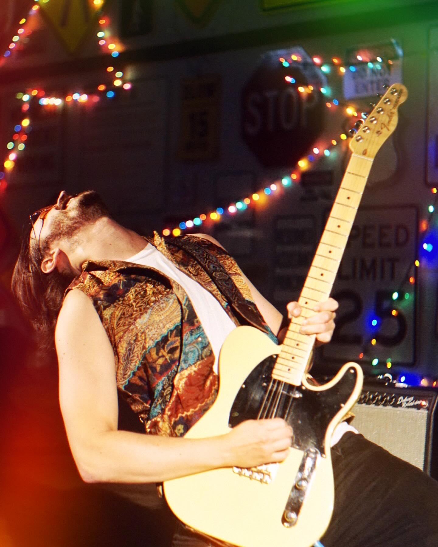 Joe Psybin in a turquoise western suit, holding a cream Telecaster